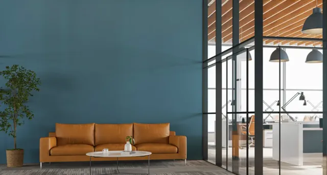 Lounge with a teal wall, tan sofa and tall windows